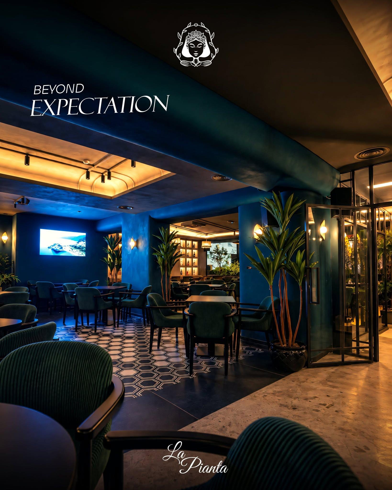 La Pianta dining room with blue walls, upholstered chairs and tall plants.